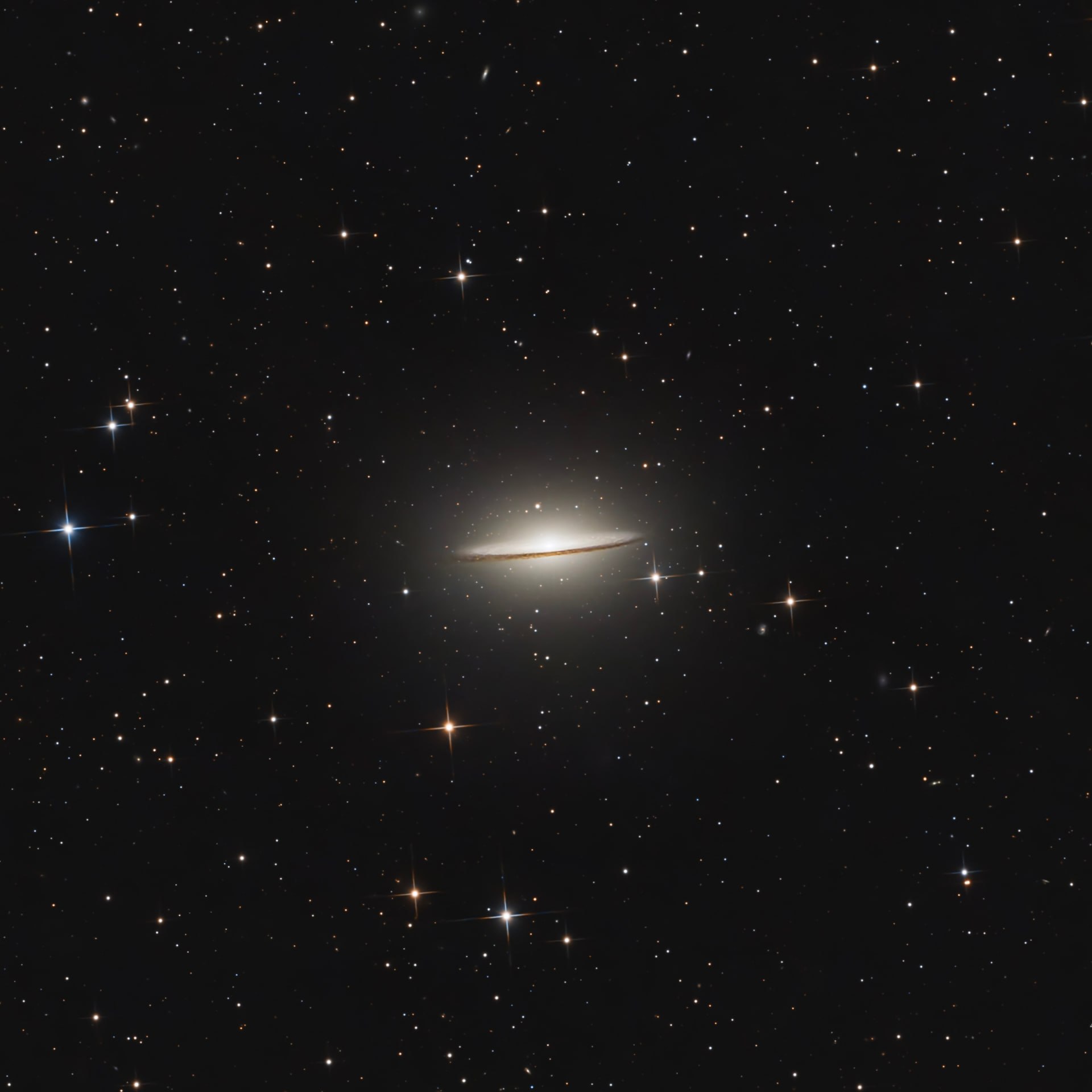 The Sombrero Galaxy seen edge-on with a thin dark dust lane and bright central bulge.