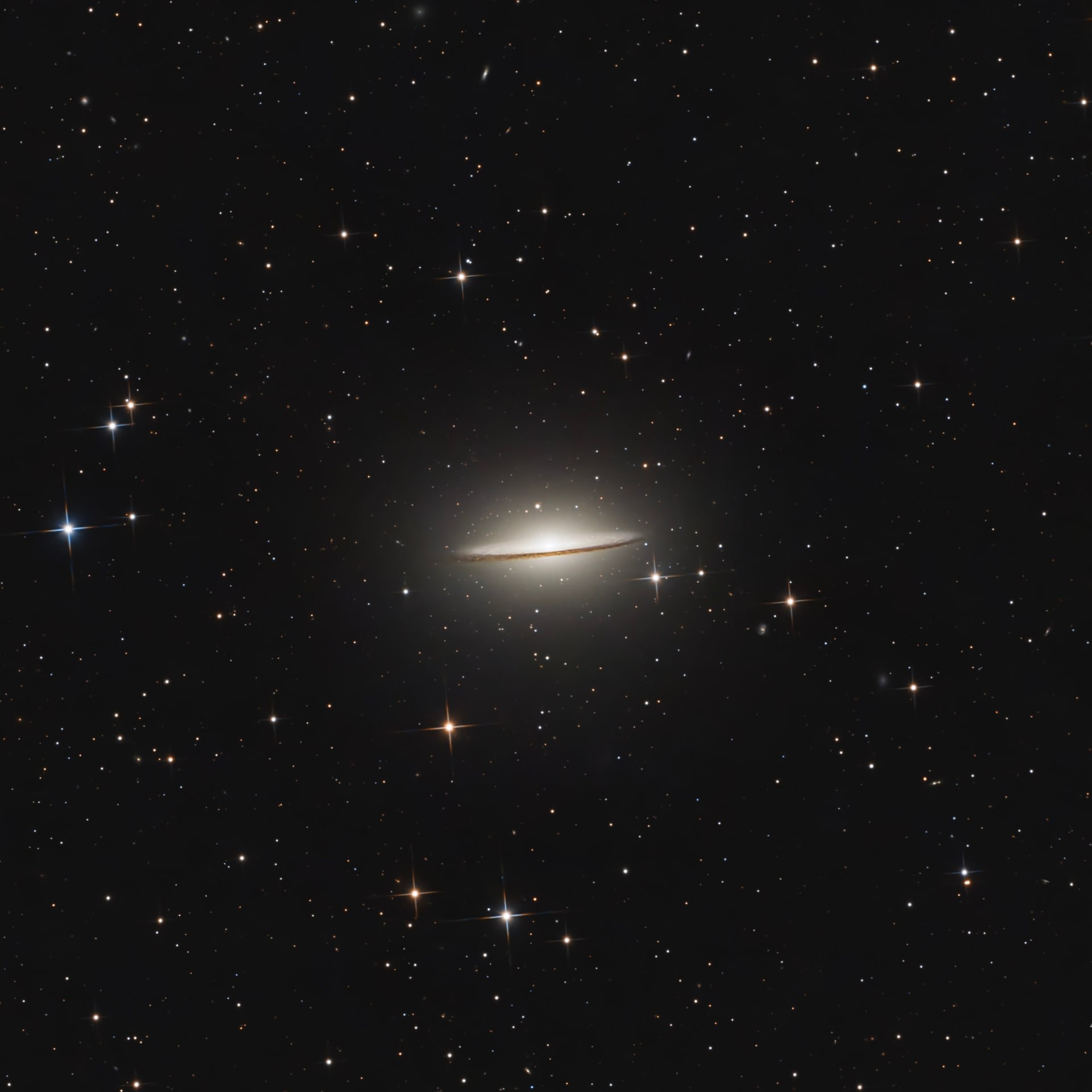 The Sombrero Galaxy seen edge-on with a thin dark dust lane and bright central bulge.